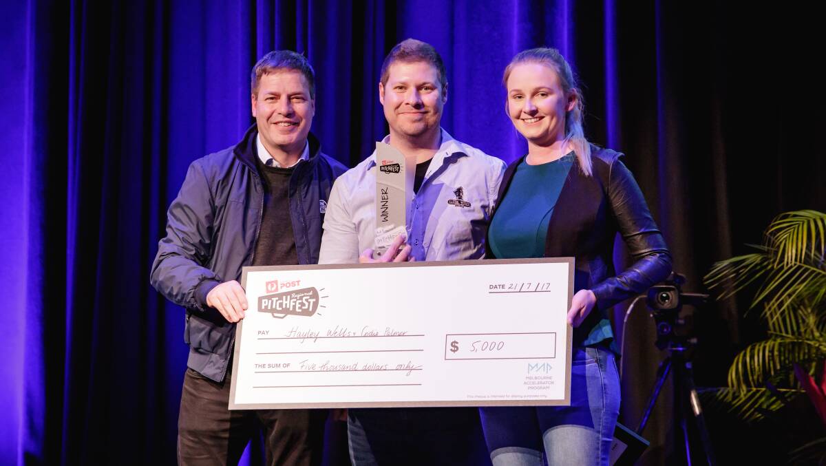 Australia Post chief innovation officer Greg Sutherland presenting Illegal Tender Rum Co. owners Codie Palmer and Hayley Wells with the WA Pitchfest prize at Bunbury Reigonal Entertainment Centre on Friday night. 