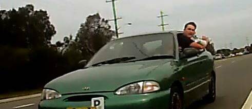 CAPTURED: A man leans from a green Hyundai Excel at Hexham and throws a plastic cup filled with ice at a cyclist. 