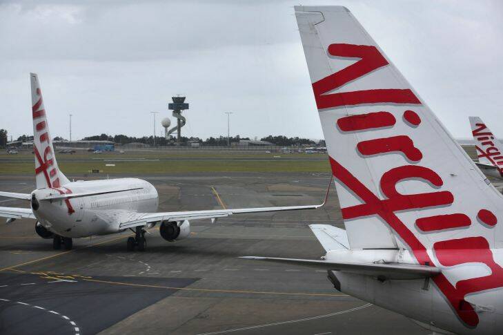 SYDNEY, AUSTRALIA - December 21, 2017: SYDNEY, AUSTRALIA - SMH NEWS: 211217: A Virgin Australia aircraft taxi's away at the tarmac whislt other planes line up at air-bridges prior to flying at Sydney's Domestic Airport. (Photo James Alcock /Fairfax Media).