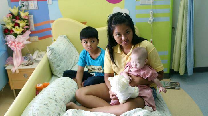 Baby Gammy with his surrogate mother Pattharamon Janbua and her 7-year-old son at a hospital in south-eastern Thailand on Sunday.  Photo: Apichart Weerawong