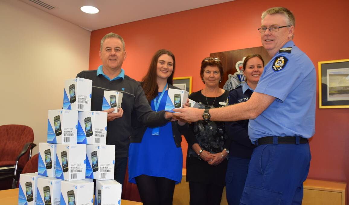 Telstra area general manager hands a phone destined for a domestic violence victim to South West family protection coordinator Don Mclean. Also pictured are Bunbury Telstra Shop sales manager Emily Ward, Waratah family and domestic violence coordinator Jo Lafferty and senior constable Clare Kelly (back).