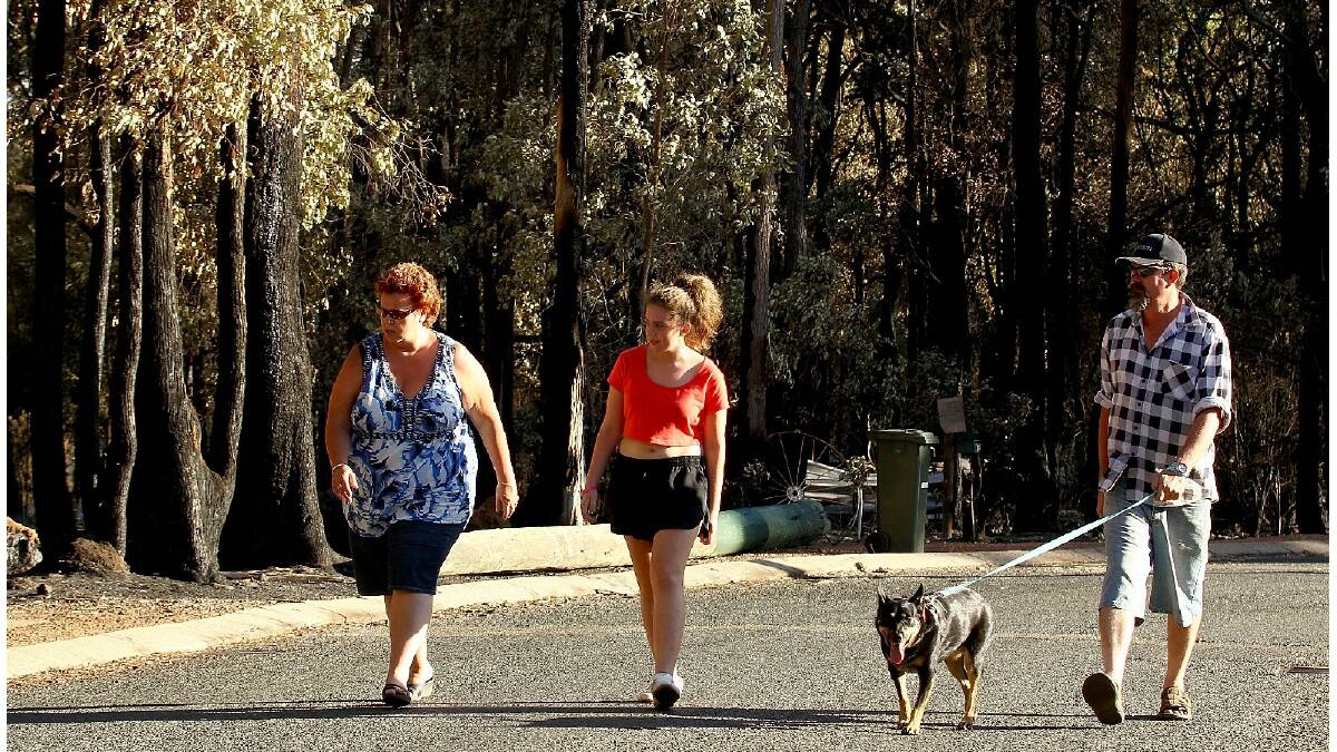Emergency services escorted residents to survey damage to their homes and properties yesterday following a bushfire that destroyed more than 50 houses. Photo: Paul Kane/Getty Images.