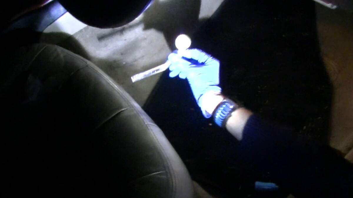 Constable Sarah Norman seizes a crack pipe concealed under the driver's seat of a vehicle.