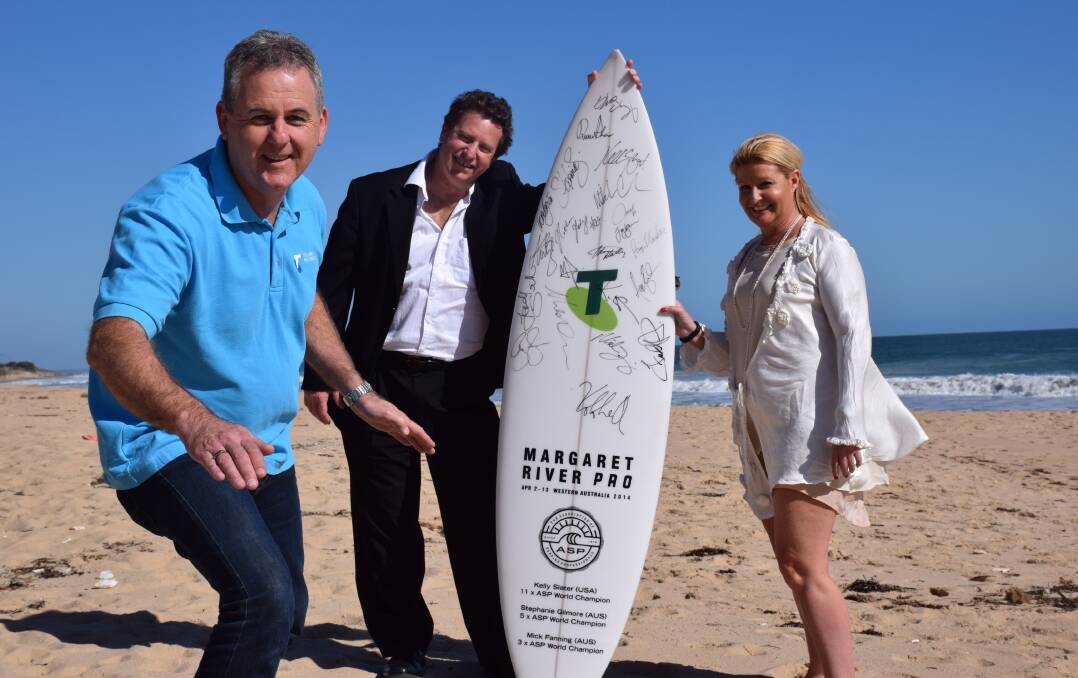 Telstra area general manager Boyd Brown catching a mock wave after handing over a signed Margaret River Pro surfboard to Save the Children representatives Anne-Marie Denny and Glen Davies.