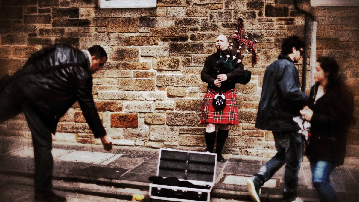 A man drops some money into a piper's case busking on the Royal Mile on April 23, 2014 in Edinburgh, Scotland. Pic: Jeff J Mitchell/Getty Images