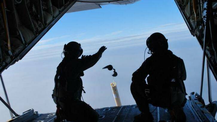 Loadmasters Sergeant Adam Roberts (left) and Flight Sergeant John Mancey launch one of two water-activated buoys from the Hercules C-130J. Photo: Liam Ducey