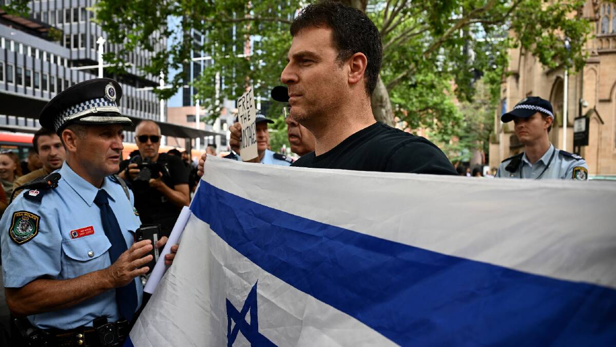 A man with an Israeli flag is spoken to by police at the School Strike 4 Palestine in Sydney on November 24. Picture by AAP Image/Dan Himbrechts