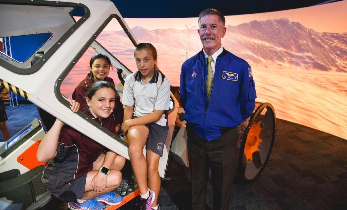 Australind students Isabella Ferrari, Airish Bargola and Beth Gallagher with NASA astronaut Jim Reilly on the surface exploration vehicle in Scitech's planet pioneers exhibition. Photo: Dan Grant.