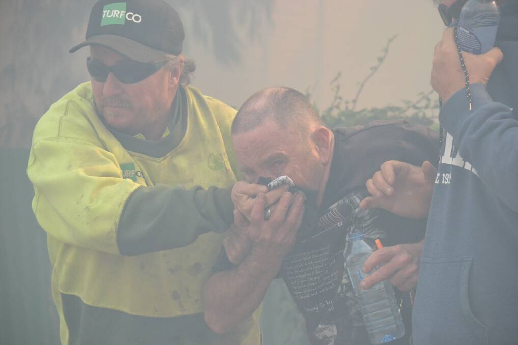 HELP: Bomaderry man Ned Ashley (centre) is taken away from the Bomaderry fire by friends at the height of Wednesday’s emergency situation suffering smoke inhalation.