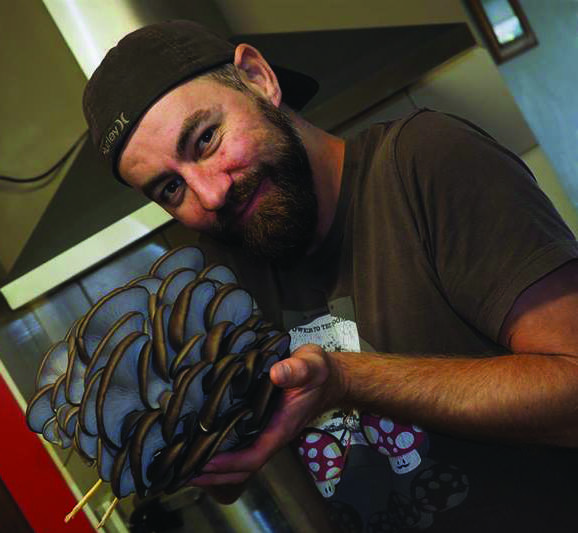 Urban Kulture founder Aaron Boyer with his mushrooms which were grown from using used coffee granules. Photo supplied.