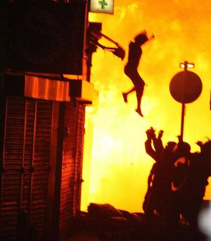 A woman leaps from a burning building in Croydon during the London riots.
